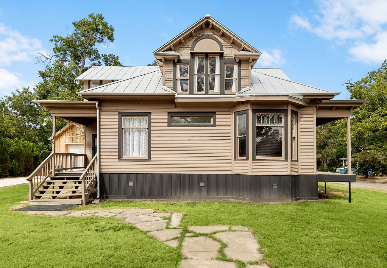 Front elevation of historic, light-filled home at Bowie & Terrell  Seguin, TX home w gabled roof, front porch, large yard plentiful parking