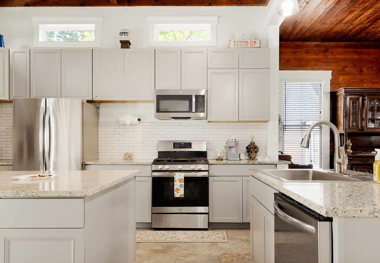 Spacious kitchen with granite countertops, and a gas range framed by warm wood ceilings and bright natural light.
